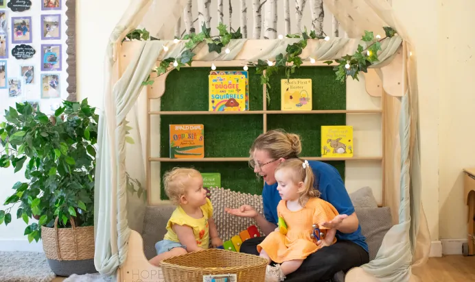 Children sitting in book corner with key worker at Kiddi Caru Day Nursery Preschool Whiteley