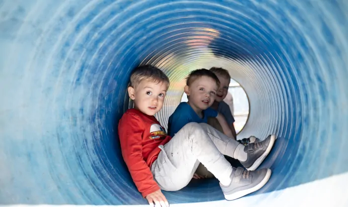 Children smiling in tunnel outside at The Kiddi Caru Day Nursery Preschool Taunton