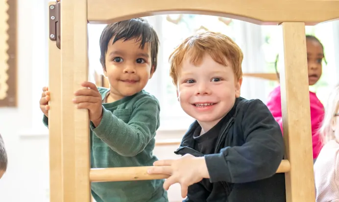 Children smiling on wooden play equipment at Little Acorns Day Nursery Preschool Stoneygate