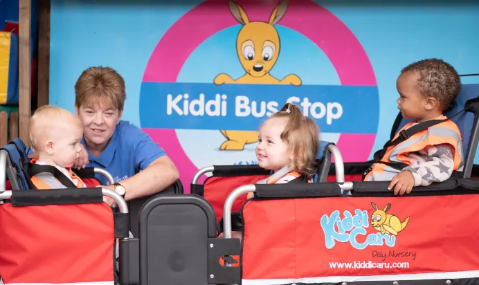children-smiling-with-key-worker-in-play-bus-stop-at-the-kiddi-caru-day-nursery-preschool-basingstoke.jpg