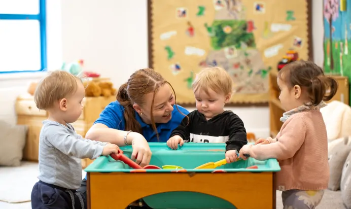 Key worker and children playing in sand pit at Kiddi Caru Day Nursery Preschool Plympton Plymouth