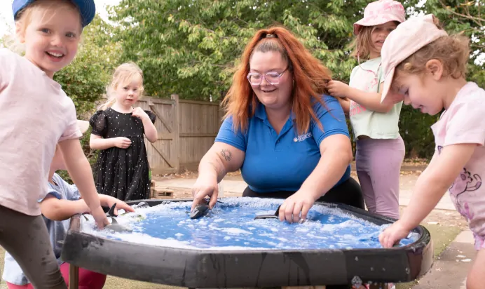 Key worker and children playing in water pit with toys at The Kiddi Caru Day Nursery Preschool Writtle