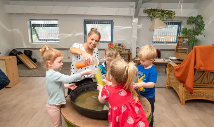 Key worker and children playing with coloured water at Kiddi Caru Day Nursery Preschool Market Harborough