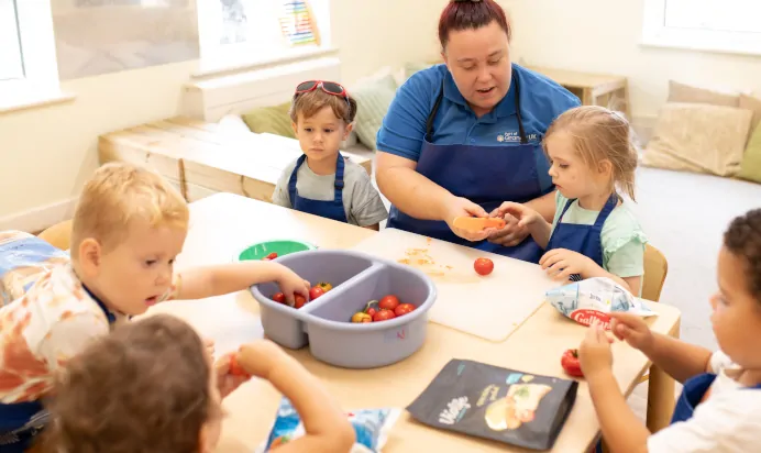 Key worker and children preparing fruit at The Kiddi Caru Day Nursery Preschool Writtle