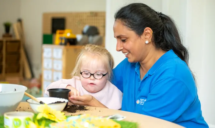 Key worker helping child plant sunflower seeds at Little Acorns Day Nursery Preschool Stoneygate