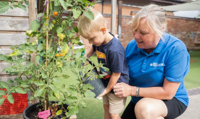 Key worker helping child water plants at The Old Barn Day Nursery Preschool Narborough