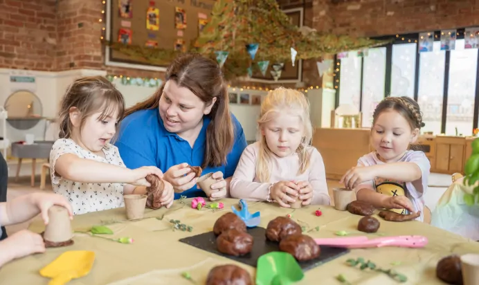 Key worker helping children with play dough at The Old Barn Day Nursery Preschool Narborough