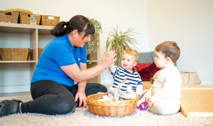 Key worker high fiving child at Kiddi Caru Day Nursery Preschool Market Harborough