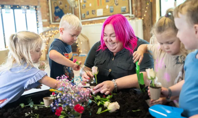 Key worker playing with children in bright interactive space at The Old Barn Day Nursery Preschool Narborough