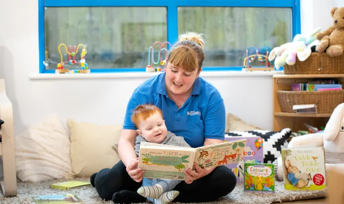 Key worker reading a book to child at Kiddi Caru Day Nursery Preschool Plympton Plymouth