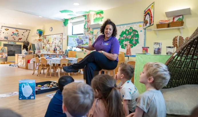 Key worker reading a book to children at Kiddi Caru Day Nursery Preschool Whiteley