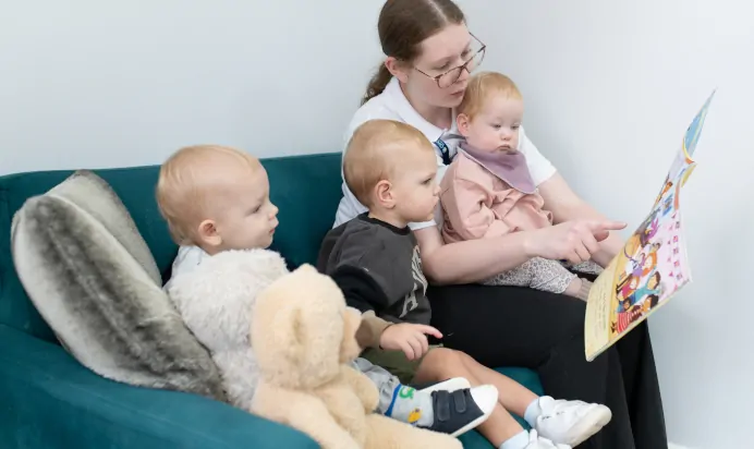 Key worker reading a book with child at The Kiddi Caru Day Nursery Preschool Basingstoke