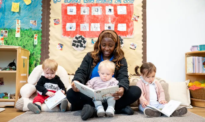 Key worker reading with children in book corner at Kiddi Caru Day Nursery Preschool Plympton Plymouth