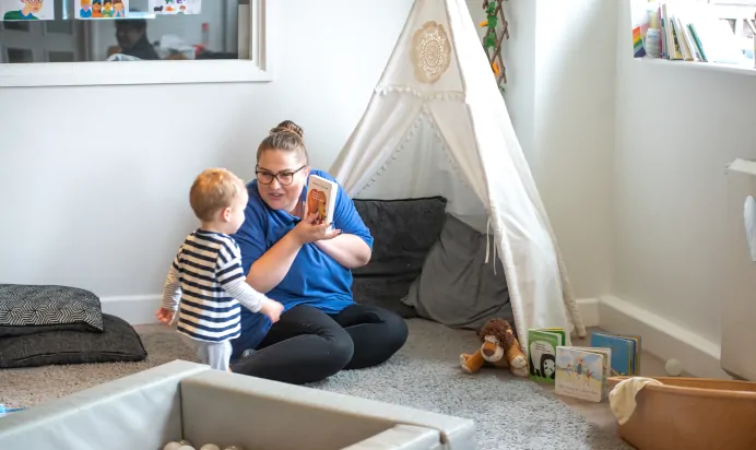 Key worker showing a child a book in a teepee at Kiddi Caru Day Nursery Preschool Market Harborough