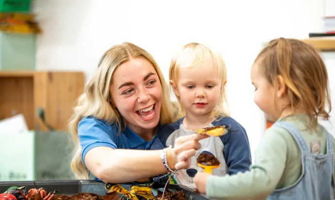 Key worker showing child a plastic bug toy at Kiddi Caru Day Nursery Preschool Plympton Plymouth