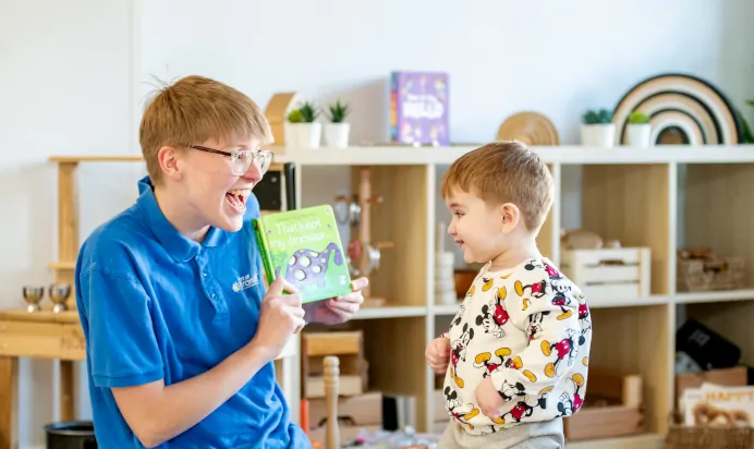 Key worker showing child thats not my dinosaur book at Kiddi Caru Day Nursery Preschool Caldecotte Milton Keynes