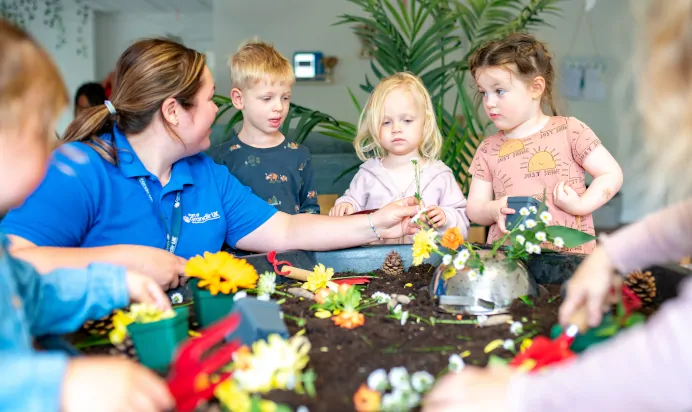 Key worker showing children flowers at Kiddi Caru Day Nursery Preschool Market Harborough