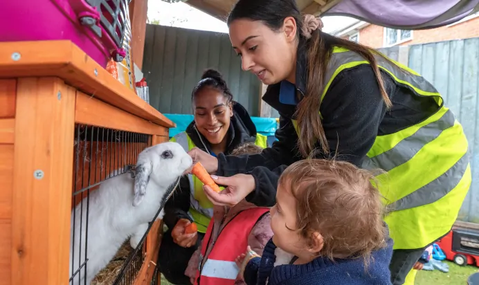 Key worker showing children how to feed a rabbit at Charnwood Day Nursery Preschool Shepshed Loughborough