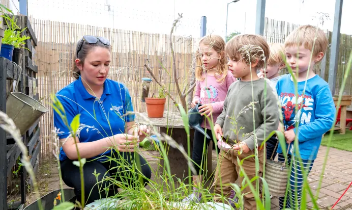 Key worker showing children plants at Kiddi Caru Day Nursery Preschool Market Harborough