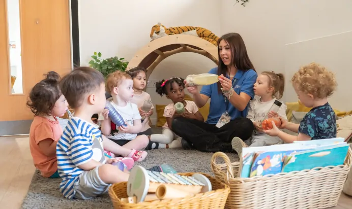 Key worker showing children science trick at Kiddi Caru Day Nursery Preschool Walnut Tree Milton Keynes