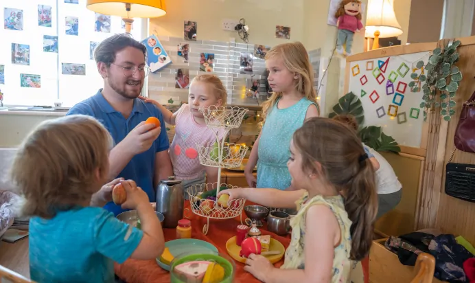 Key worker teaching children fruits at Kiddi Caru Day Nursery Preschool Leighton Buzzard
