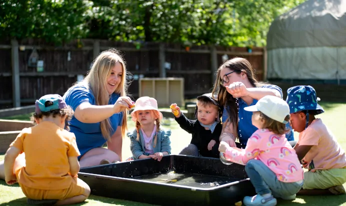 Key workers and children playing with water at Kiddi Caru Day Nursery Preschool Wellingborough