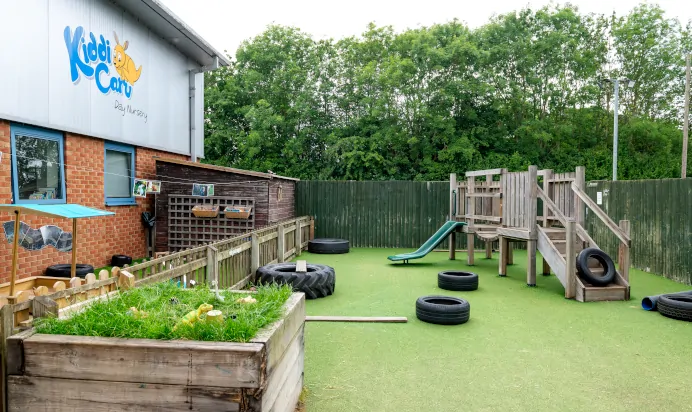 Outdoor play area with wooden frame at Kiddi Caru Day Nursery Preschool Market Harborough