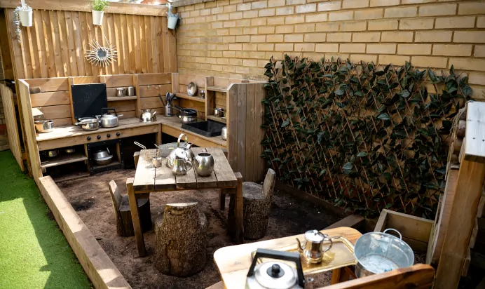 Outdoor play kitchen with pots and pans at Kiddi Caru Day Nursery Preschool Caldecotte Milton Keynes