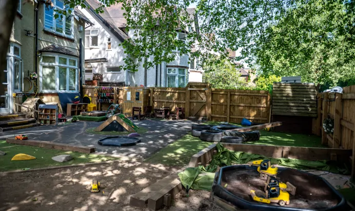 Play area for children outdoors with dirt pit and diggers at Kiddi Caru Day Nursery Preschool Abington Park Northampton