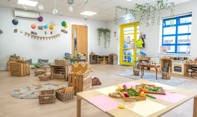 Play area indoors with wooden toys and play kitchen at Kiddi Caru Day Nursery Preschool Caldecotte Milton Keynes