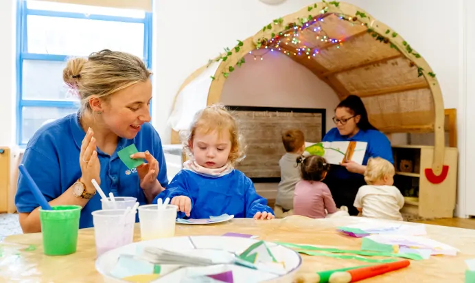 Small child working on some art wtih a key worker at Kiddi Caru Day Nursery Preschool Torquay