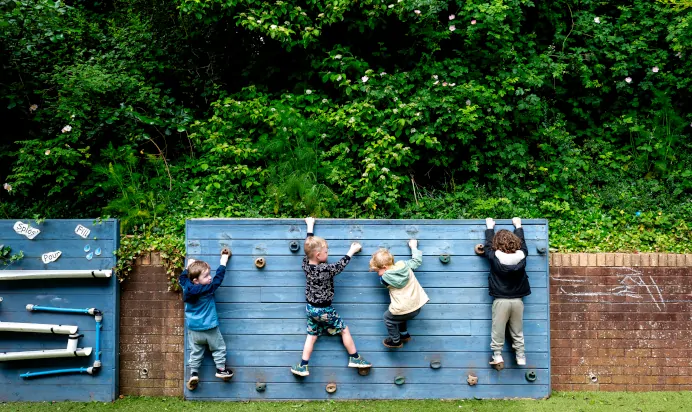 Small children climbing on outside playing equipment at The Kiddi Caru Day Nursery Preschool Torquay