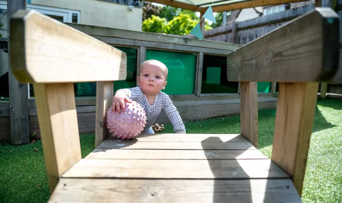 Toddler playing with sensory ball outside at Kiddi Caru Day Nursery Preschool Abington Park Northampton