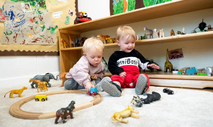 Two children playing with wooden toy cars at Kiddi Caru Day Nursery Preschool Plympton Plymouth