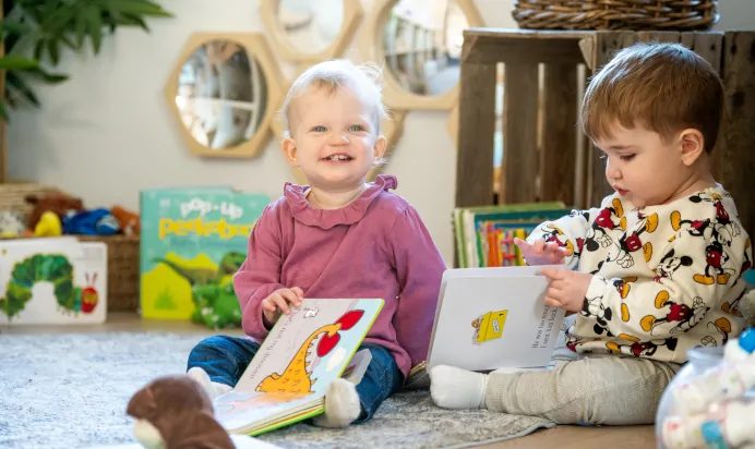 Two children reading books indoors at Kiddi Caru Day Nursery Preschool Caldecotte Milton Keynes