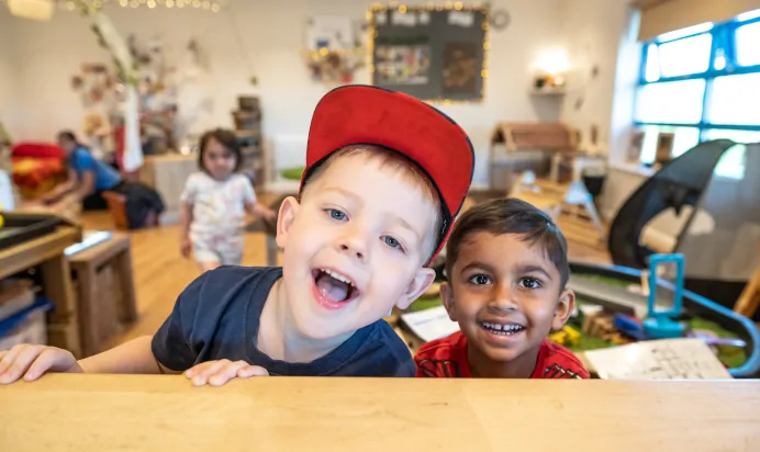 Two children smiling at Kiddi Caru Day Nursery Preschool Wellingborough
