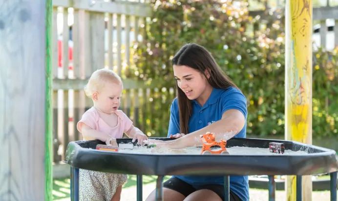 Child and key worker playing in sand pit at Kiddi Caru Day Nursery Preschool Market Ower