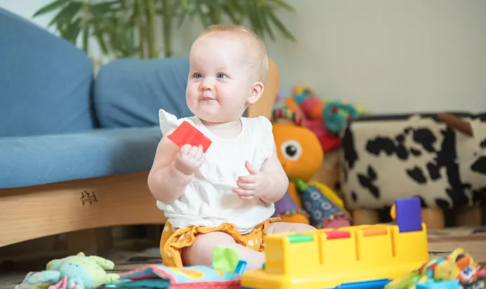 Child holding red block at Kiddi Caru Day Nursery Preschool Market Ower
