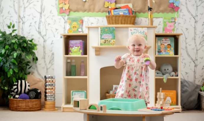 Child playing with toy and smiling at Kiddi Caru Day Nursery Preschool Fareham