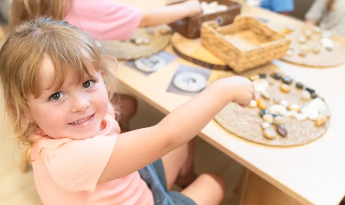 Child pointing to stones and smiling at Kiddi Caru Day Nursery Preschool Market Ower