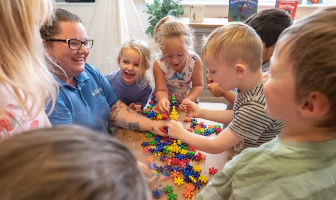 Children and key worker laughing whilst playing with toys at Kiddi Caru Day Nursery Preschool Fareham