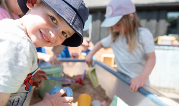 Children playing in sand pit outside at Kiddi Caru Day Nursery Preschool Market Ower