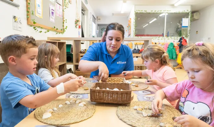 Key worker and children playing with pebbles at Kiddi Caru Day Nursery Preschool Market Ower