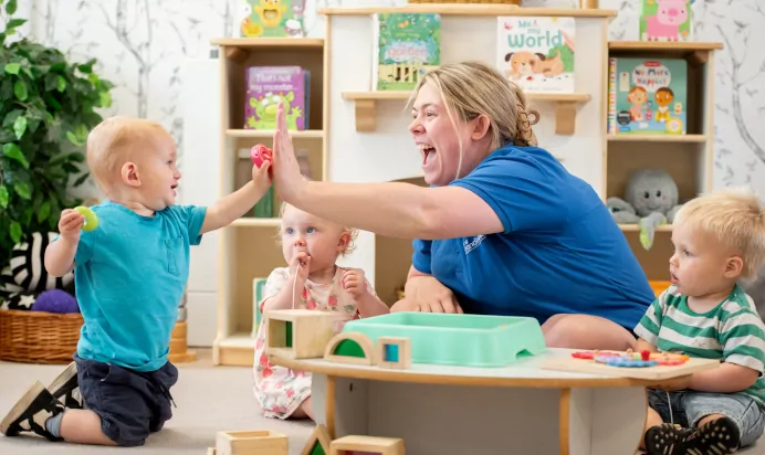 Key worker high fives child at Kiddi Caru Day Nursery Preschool Fareham