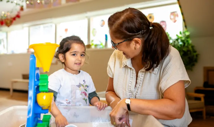 Child and key worker playing in water tray at Dicky Birds Nursery Preschool Claremont Road Surbiton