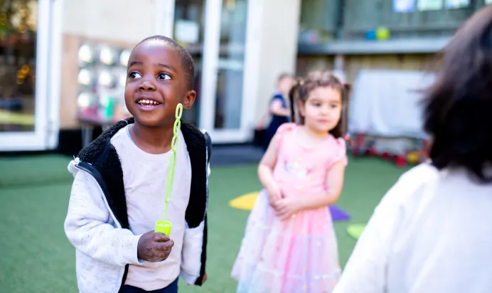 Child playing with bubble wand at Dicky Birds Nursery Preschool Claremont Road Surbiton