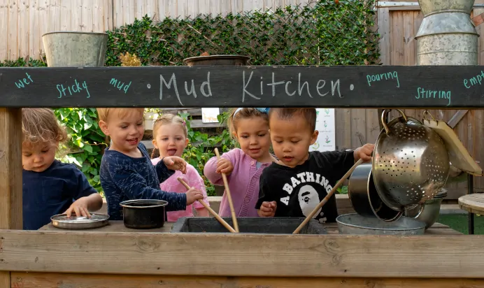 Children playing in the mud kitchen at Dicky Birds Nursery Preschool Queens Road Wimbledon London