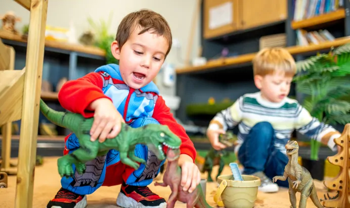 Children playing with toy dinosaurs in the sand pit at Dicky Birds Nursery Preschool Claremont Road Surbiton