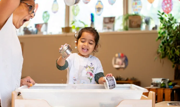Key worker and child playing with water at Dicky Birds Nursery Preschool Claremont Road Surbiton