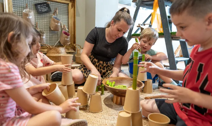 Key worker and children stacking wooden cups at Dicky Birds Nursery Preschool Raynes Park London